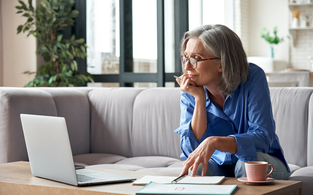 Older woman in her 60's with gray hair looking at open laptop